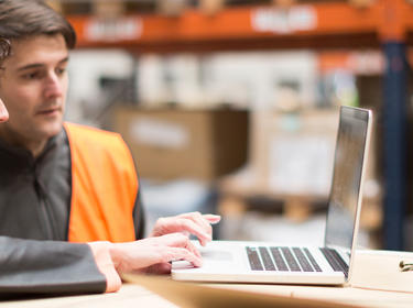 Two warehouse workers looking at a computer 