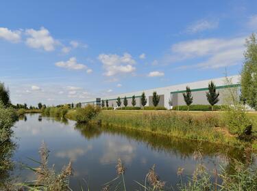 A warehouse with trees and a river in the background
