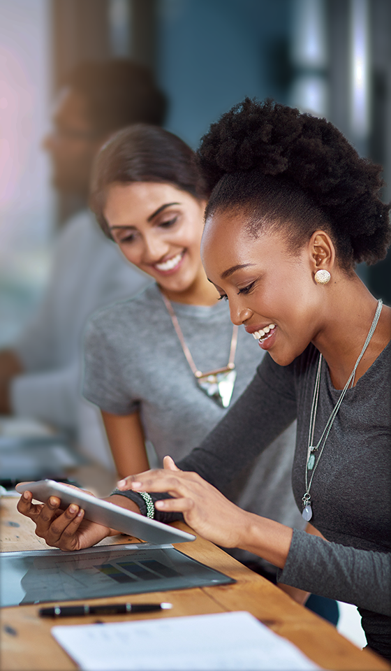 Due donne che sorridono e guardano un iPad Due donne che sorridono e guardano un iPad